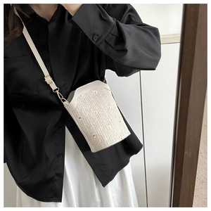 Détail du sac bandoulière en paille d'été avec broderie marguerite et fine lanière