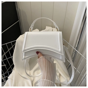 Détail d'un sac à main trapèze blanc brillant avec des finitions métalliques dorées