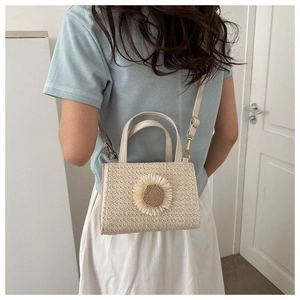 Detail of hand-woven beige straw bag featuring a large 3D sunflower and gold hardware