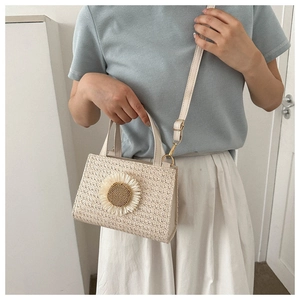 Detail of straw woven crossbody bag featuring a large sunflower and adjustable strap