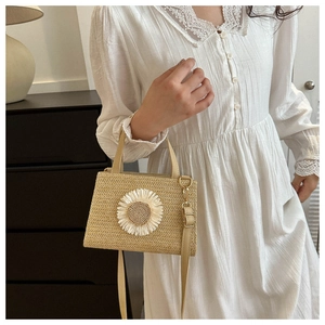 Detail of straw woven bag featuring a large white sunflower and adjustable shoulder strap