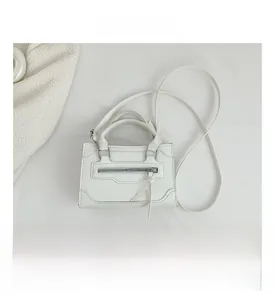 Detailed close-up of white PU leather crossbody bag featuring stitching and front zipper