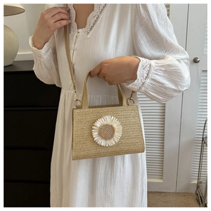 Detail view of woven straw crossbody bag with large white fabric daisy decoration