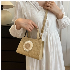 Model showcasing beige woven straw crossbody bag with 3D daisy flowers and leather strap