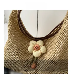 Detail of straw woven tote bag featuring a yellow crochet flower and brown leather strap