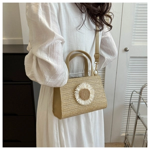 Detail of hand-woven straw crossbody bag with 3D white daisy flower and adjustable strap