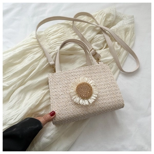 Close-up of woven cream crossbody bag featuring a 3D daisy flower and gold hardware