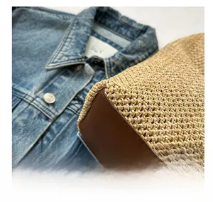 Detail shot of the woven straw and dark brown leather stitching on a stylish tote bag