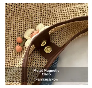 Detail of woven straw bag showing golden magnetic buckle and decorative fabric flowers