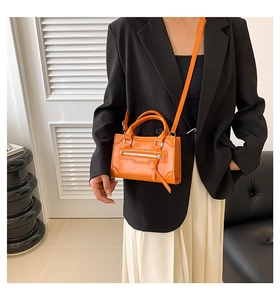 Orange PU leather crossbody bag worn by a model in a stylish indoor setting