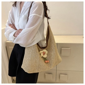Close-up of large woven shoulder bag with floral charm and brown leather strap