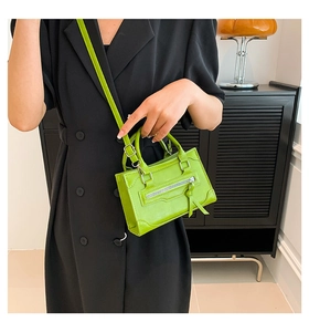 Close-up of vibrant green PU leather crossbody bag with decorative stitching and zipper