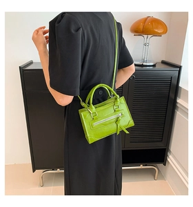 Fashionable bright green leather handbag with decorative tassels worn by model
