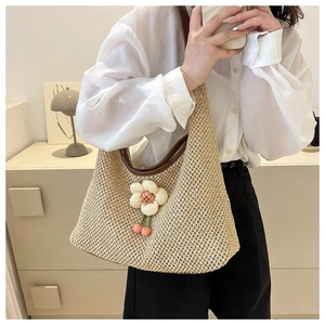 Detail of beige woven shoulder bag featuring a 3D floral accent and brown leather strap
