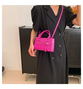 Detail of fuchsia PU leather mini crossbody bag with tassels and silver zipper