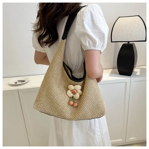 Detail of handwoven straw tote with black PU straps and delicate floral 3D ornament