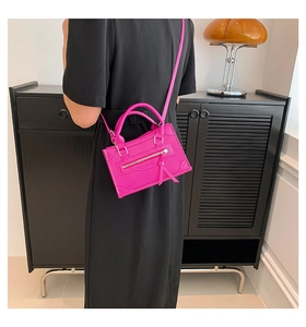 Model showing a hot pink mini crossbody bag with tassels and silver zipper detail