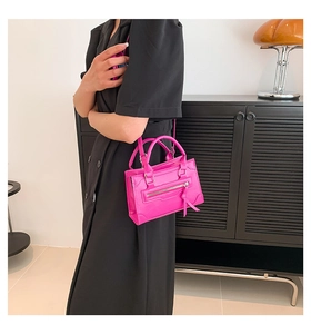 Close-up of rose red glossy leather mini handbag with silver zipper and tassel detail