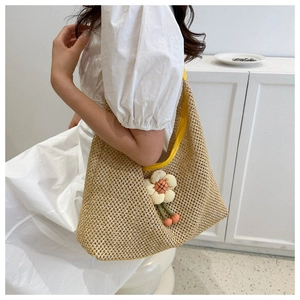 Close-up of woven straw tote bag with floral applique and cherry charm details
