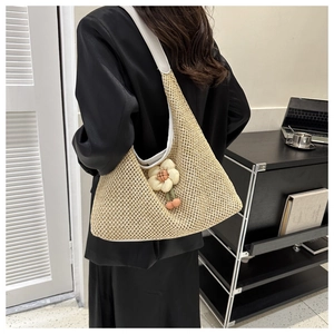 Detail view of woven straw tote bag with white leather strap and floral cherry charm