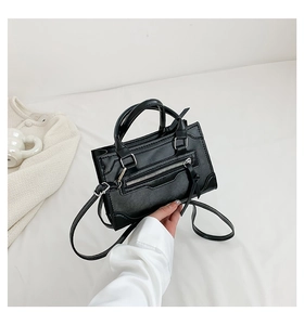 Detail of a black leather handbag with silver hardware and decorative curved stitching