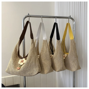 Detail of woven straw tote bags in four colors featuring floral charms and leather straps