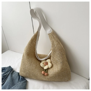 Detail of hand-woven straw shoulder bag with leather strap and decorative 3D flower charm