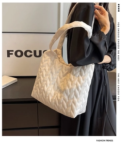 Detail of white quilted puffer shoulder bag with leaf-vein texture worn by a model