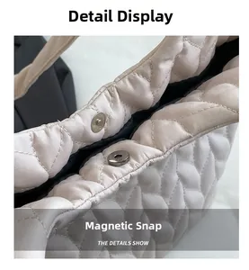 Detail shot of the magnetic snap closure on a beige quilted tote bag with black lining