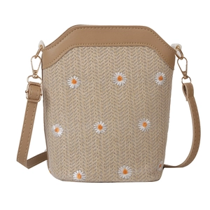Woven straw crossbody bag with white daisy embroidery and adjustable leather strap