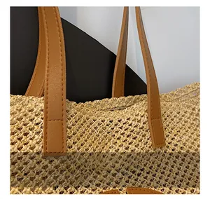 Detail showing high-quality stitching on brown leather handle of woven straw tote bag
