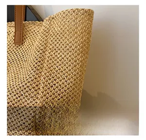 Detailed close-up of natural straw weave texture and brown leather handle stitching