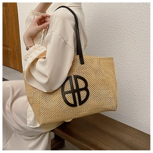 Detail of a beige woven tote bag with brown leather handles and a circular HB logo patch