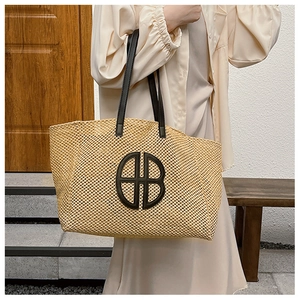 Detail of woven straw tote bag with black leather straps and HB logo embroidery