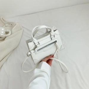 Minimalist white leather tote bag with decorative zipper and top handle shown in hand