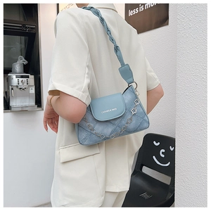 Detail of light blue denim textured shoulder bag with floral chain and woven strap
