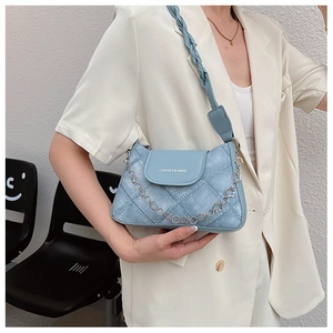 Quilted light blue denim shoulder bag with chain strap worn over a cream blazer