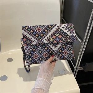 Macro view of geometric jacquard patterns and gold flower buckle on the clutch bag