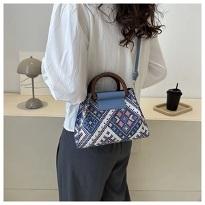 Detail van de etnische geweven crossbodytas met blauwe patronen en houten handvat
