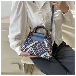 Detail van etnische geweven handtas met blauwe leren flap, houten handvat en goud beslag