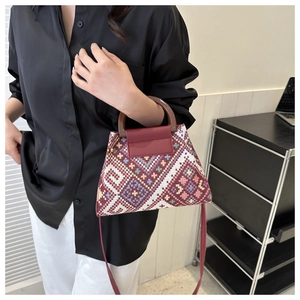 Etnische crossbody tas met rode lederen klep en houten handvat aan een model