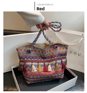 Close-up of bohemian woven tote bag with colorful tassels and braided handles in a gift box