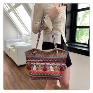 Detail of bohemian woven tote bag with colorful tassels and ethnic pattern strap