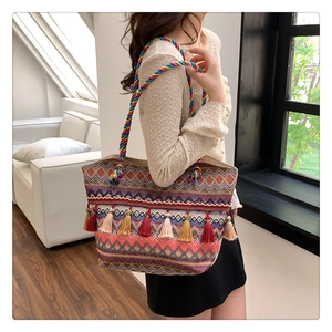 Detailed view of woven tote bag with colorful tassels and braided shoulder strap