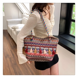 Detail of colorful woven tote bag with tassel fringe decoration and rope handles