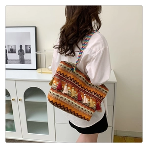 Detail of bohemian woven tote bag featuring colorful tassels and rainbow braided shoulder strap