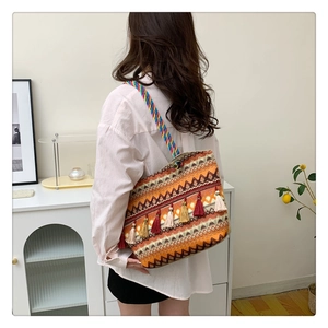Detail of bohemian woven tote bag with orange geometric patterns and colorful tassels