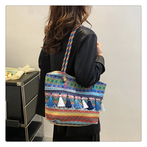 Detail of colorful woven tote bag with tassels and twisted rope shoulder strap shown on model