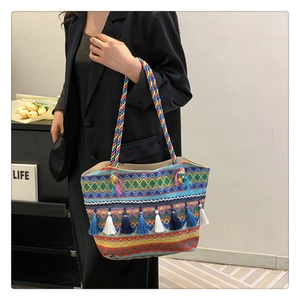 Close-up of Bohemian woven tote bag featuring colorful geometric patterns and blue tassels