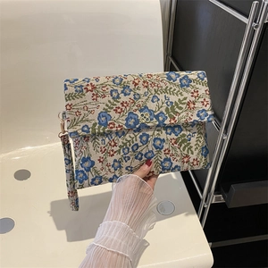 Close-up of floral jacquard envelope clutch bag with a golden clover metal buckle